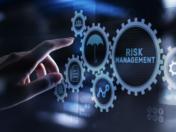 Integrated Risk Management show a fingera bout to touch a screen with cogs and risk manamgement wrtting within the cogs